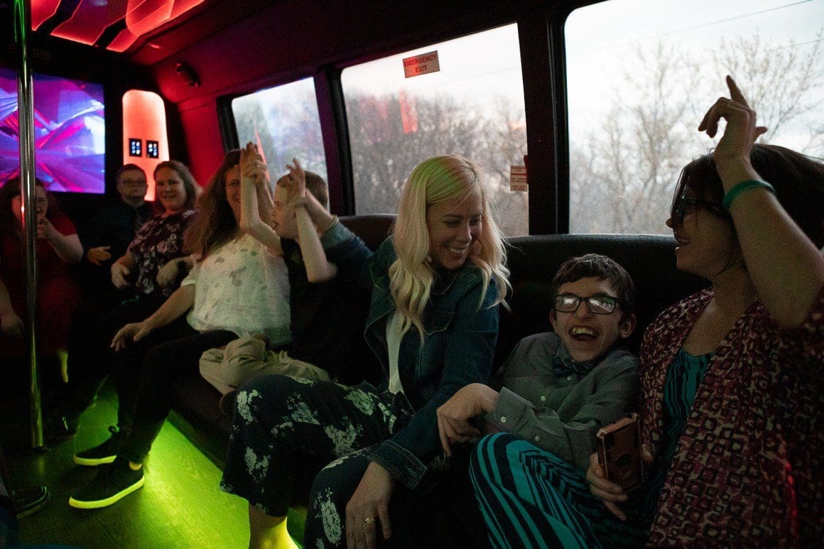 Sam Wright sings along to Miley Cyrus’s “Party in the U.S.A.” as he is sandwiched between two paraeducators from Nebraska City High School. Photo by Liz McCue for the Flatwater Free Press